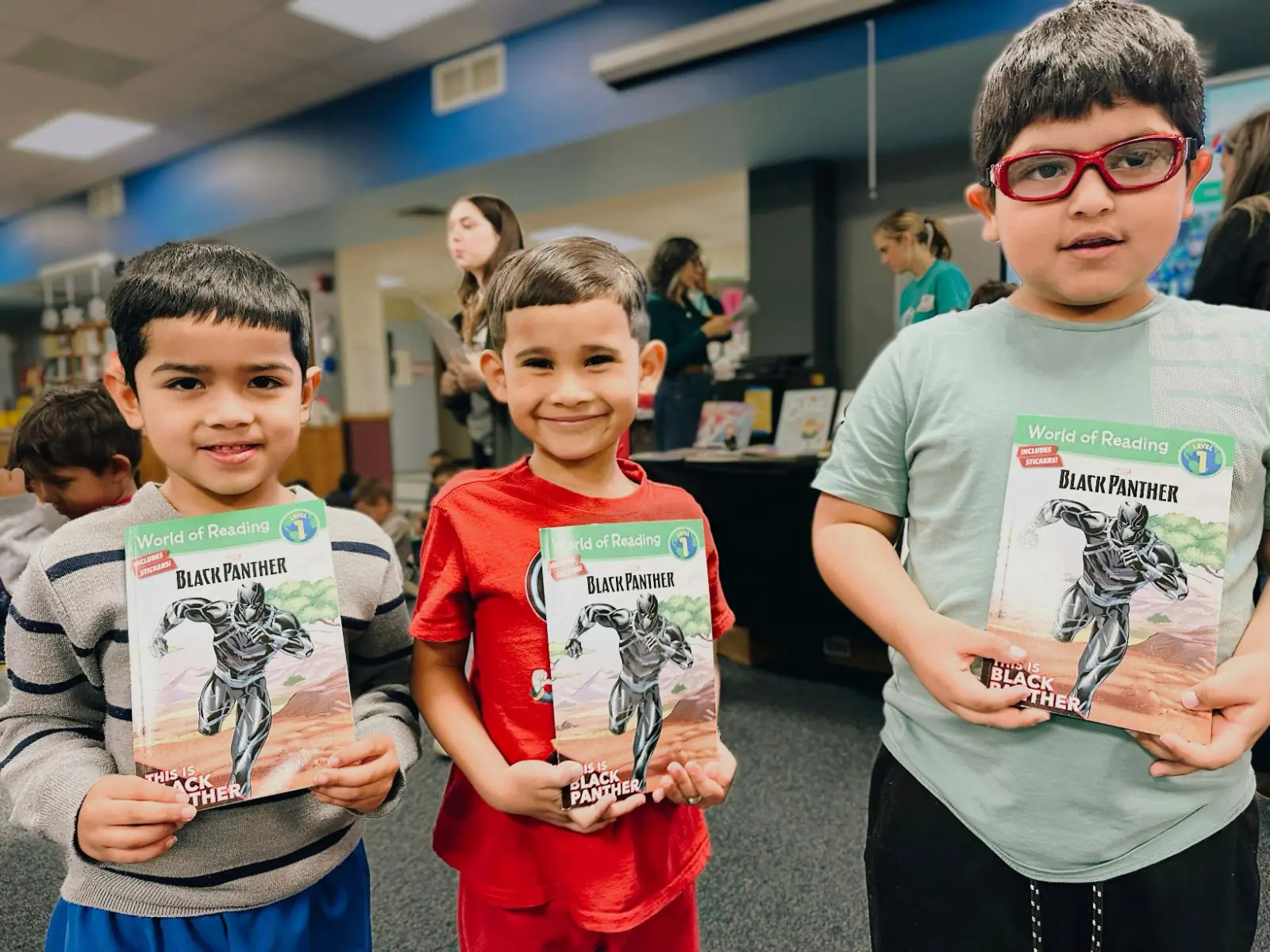 Three boys show off the same brand-new Black Panther book they each chose at a book fair