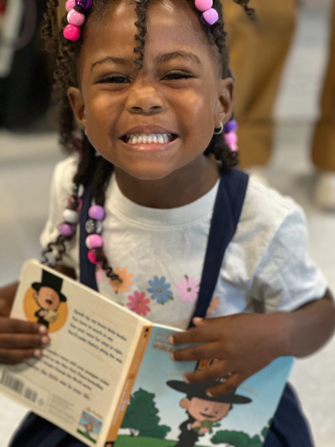A young student grins ear to ear holding the brand-new book she chose