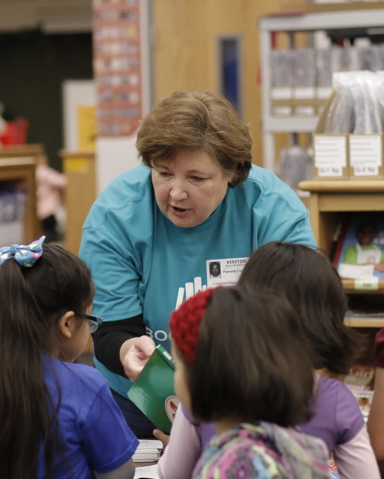 A volunteer helps students find their books at Lakeland Elementary