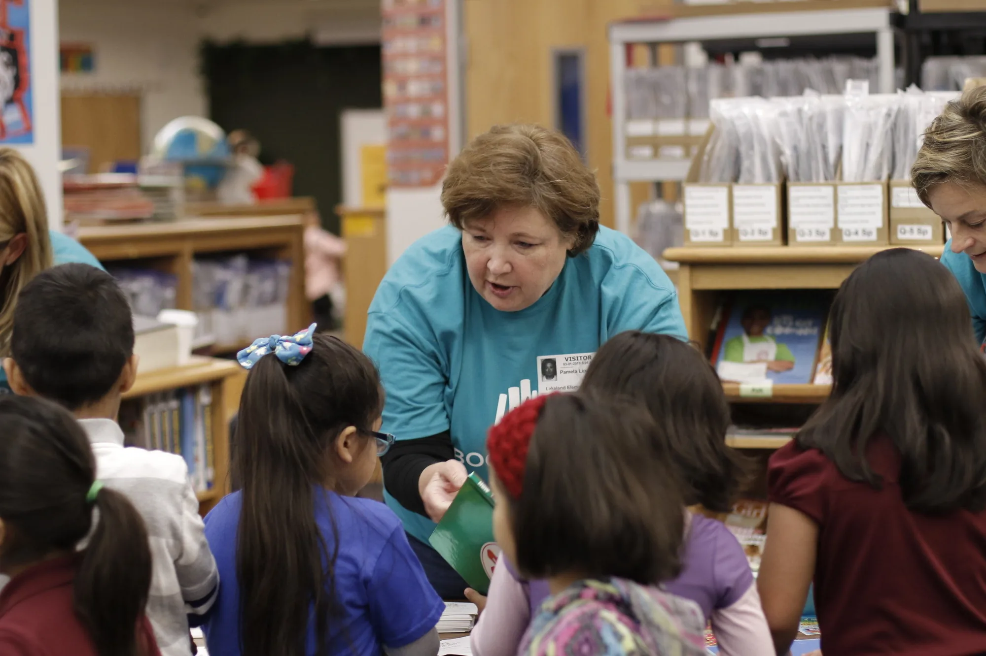 A volunteer helps students choose books at a Lakeland Elementary book fair