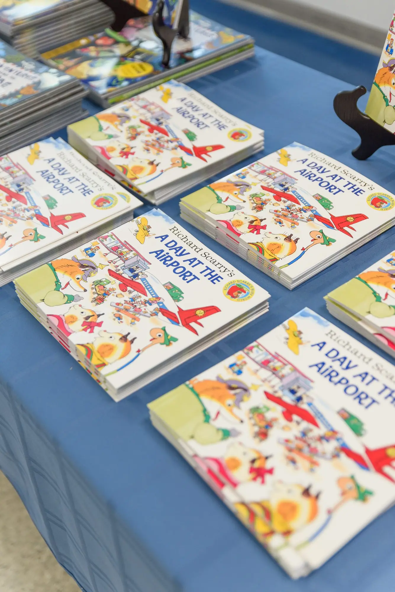 Stacks of brand-new books arranged on the Book Drive for Kids tablecloth before students arrive