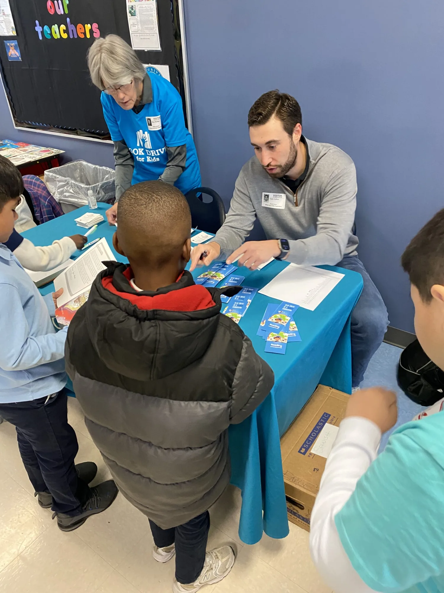A volunteer walks students through the bookmark table at a school book fair