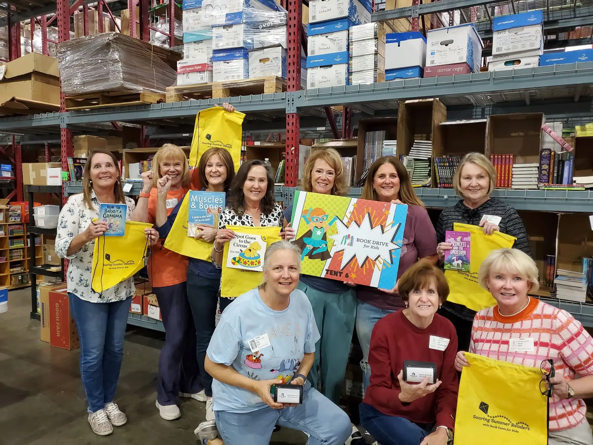 Women of Coppell volunteers with Soaring Summer Readers bags at the Book Drive for Kids warehouse